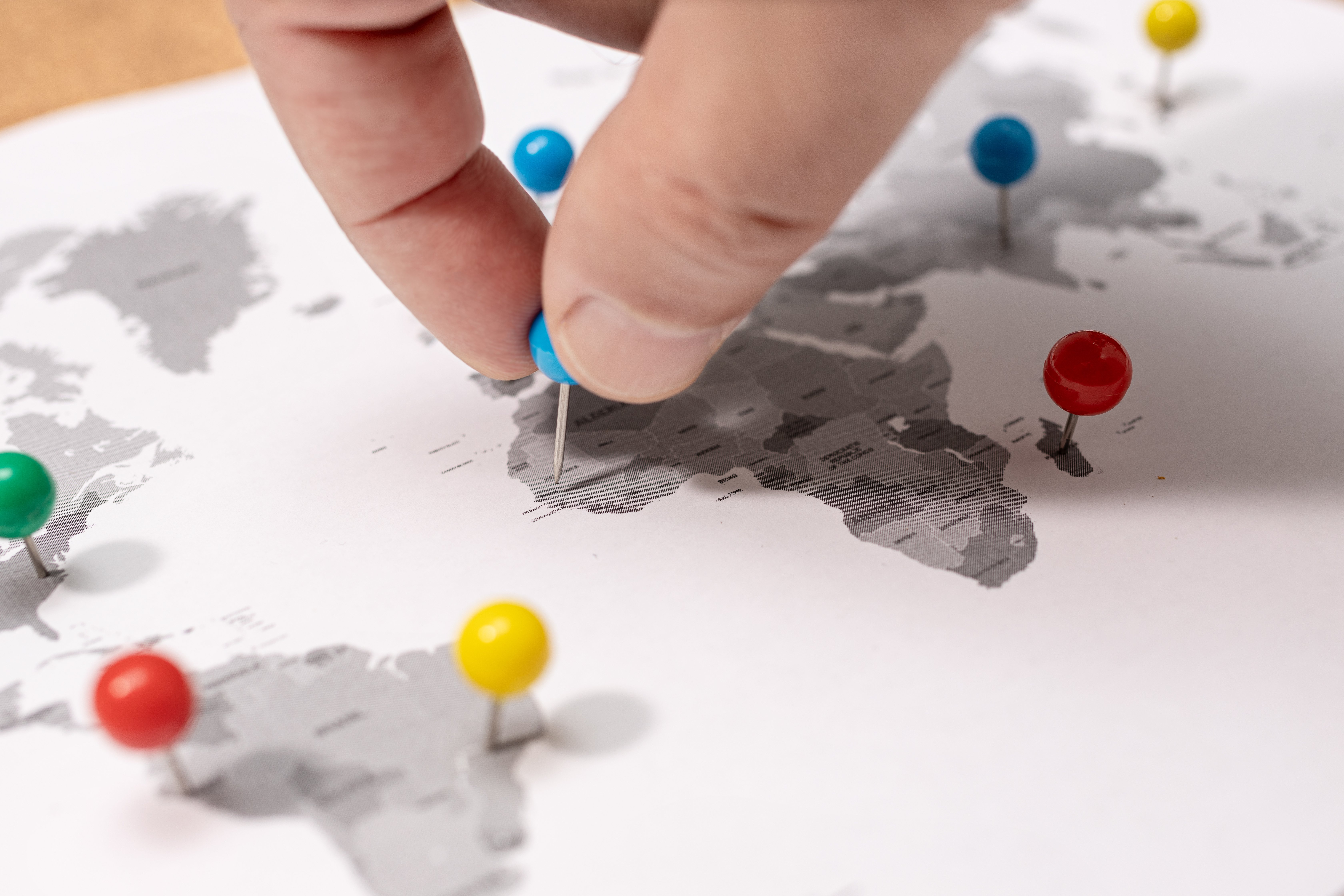 close-up-human-hand-pinning-world-map-travel-destination-concept
