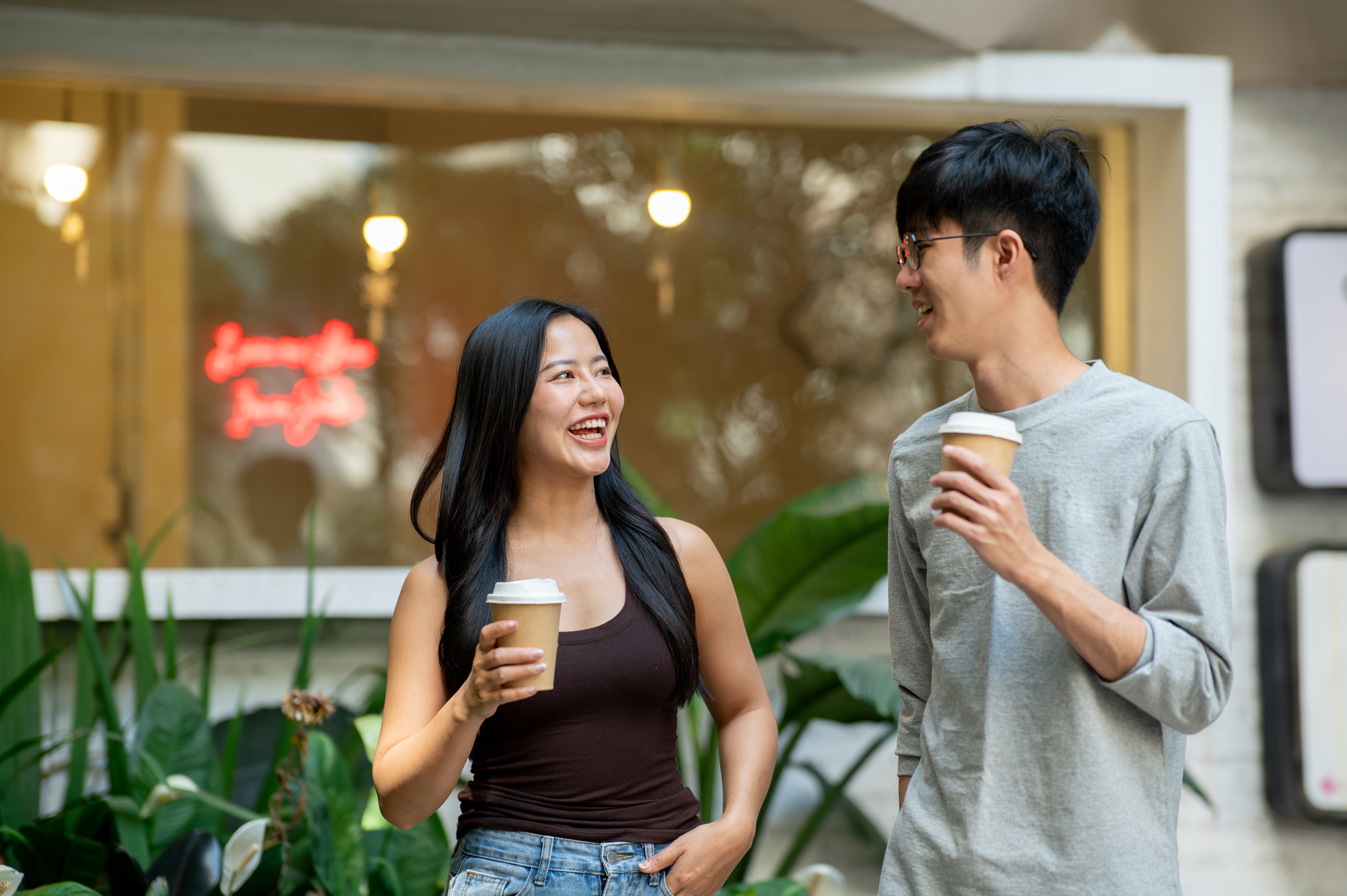 two-cheerful-asian-people-are-enjoying-conversation-coffee-while-walking-out-coffee-shop