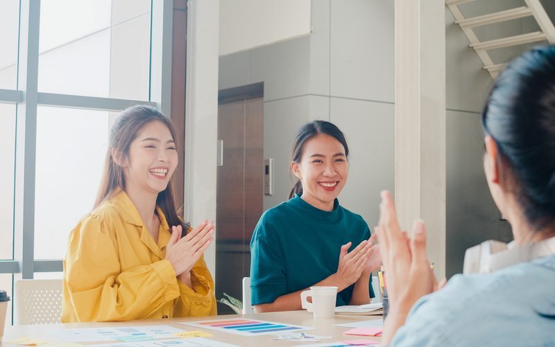 Colleagues applauding a teammate in a casual office meeting