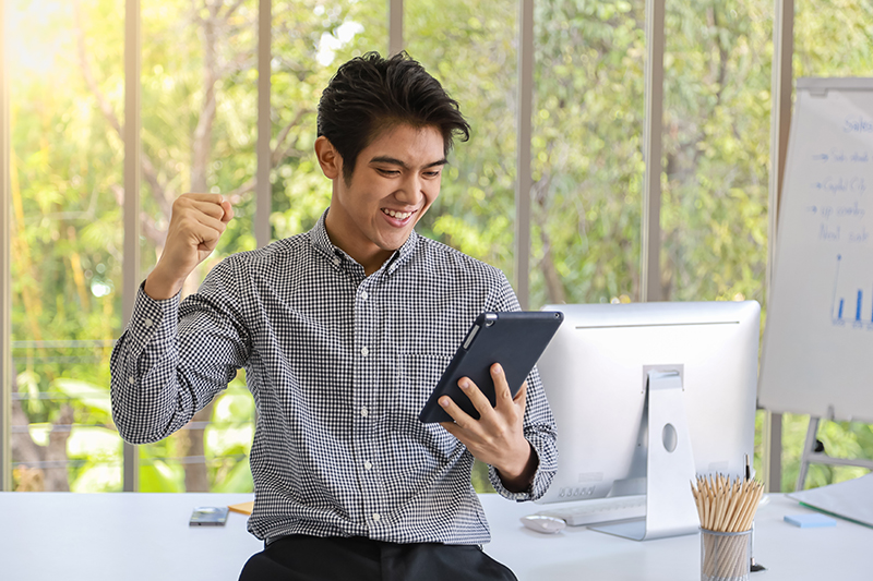 Confident young Asian businessman holding a tablet in a modern office